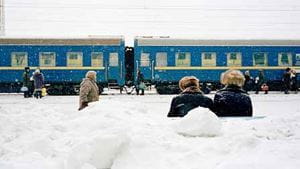 Passengers sit on a bench in the heavy snow, as the Trans-Siberia Express pulls into a station